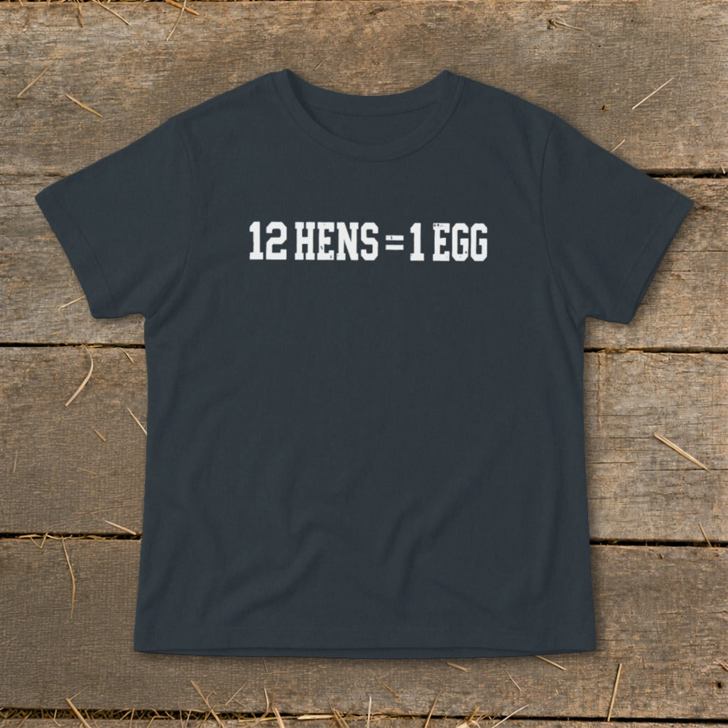 A dark gray t-shirt with the white text 12 HENS = 1 EGG laid flat on a rustic wooden background.