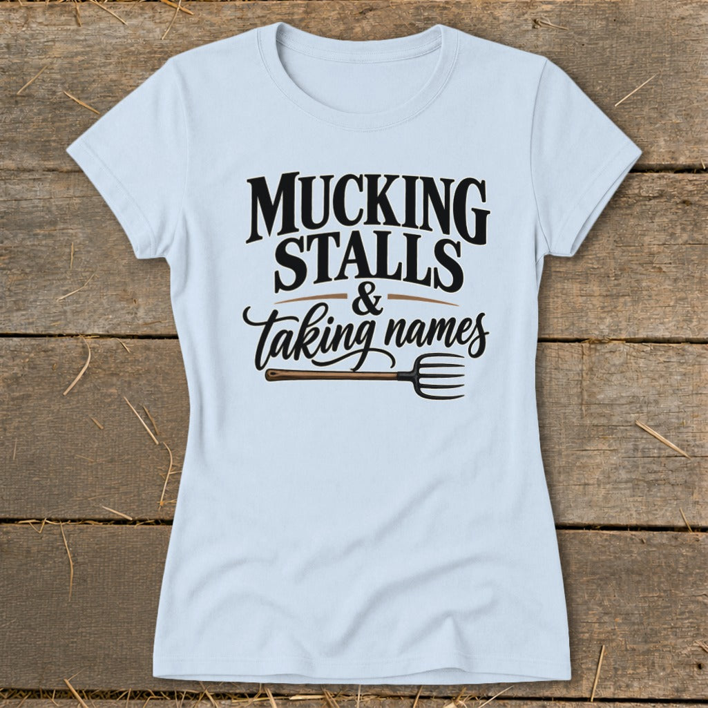 Light blue t-shirt with black text that reads "MUCKING STALLS & taking names" and a pitchfork graphic.