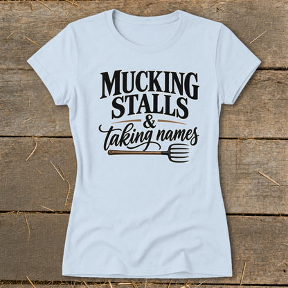 Light blue t-shirt with black text that reads "MUCKING STALLS & taking names" and a pitchfork graphic.