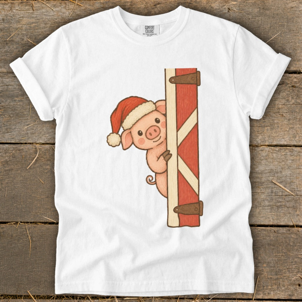 Pig wearing a Santa hat peeking around a red barn door.