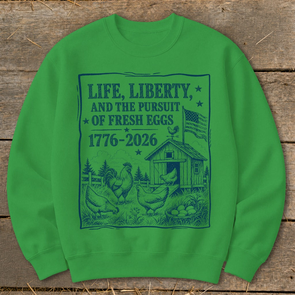 Green sweatshirt with "Life, Liberty, and the Pursuit of Fresh Eggs 1776-2026" and farm scene.