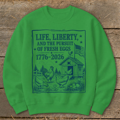 Green sweatshirt with "Life, Liberty, and the Pursuit of Fresh Eggs 1776-2026" and farm scene.