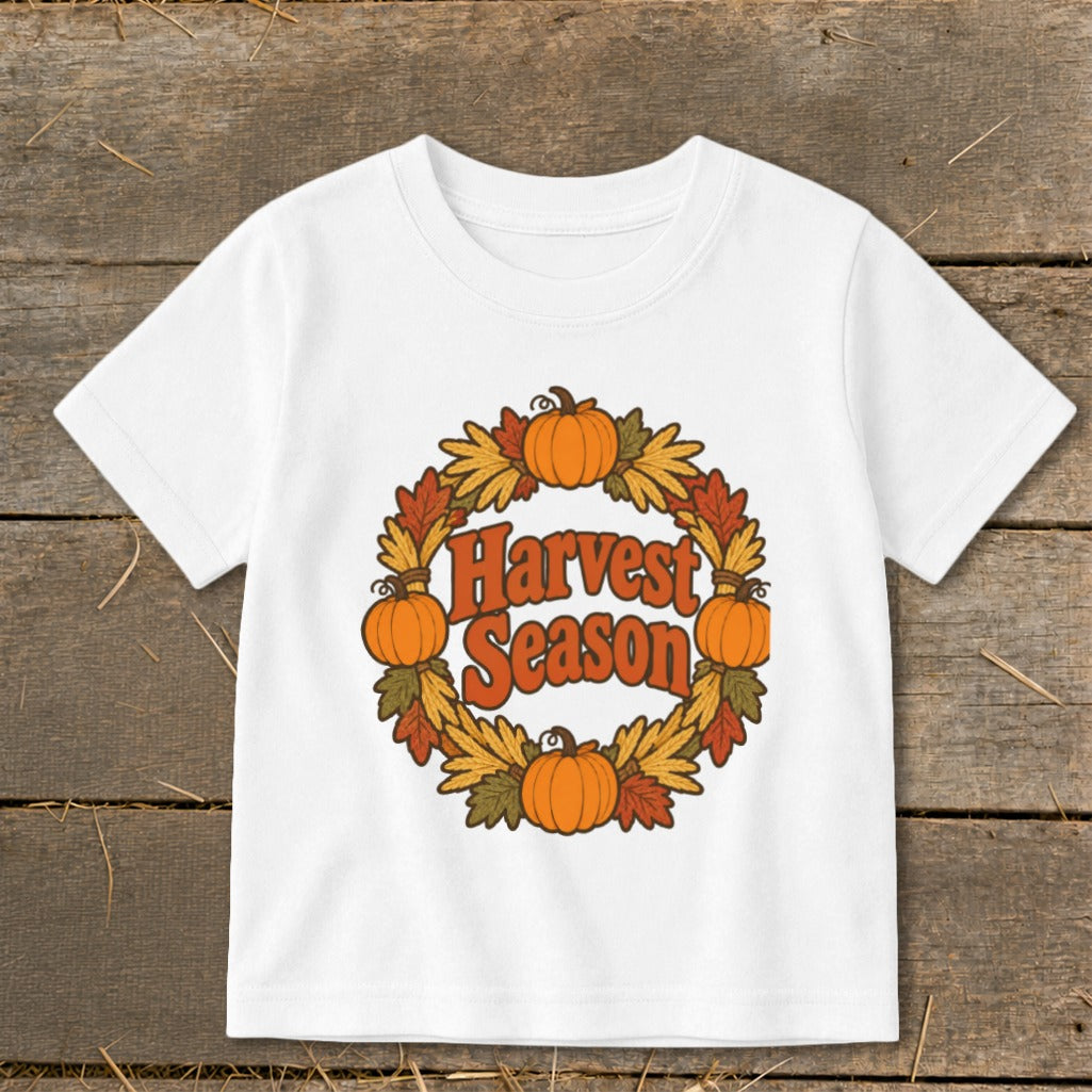 White t-shirt with a circular fall leaf wreath and pumpkins, text "Harvest Season".