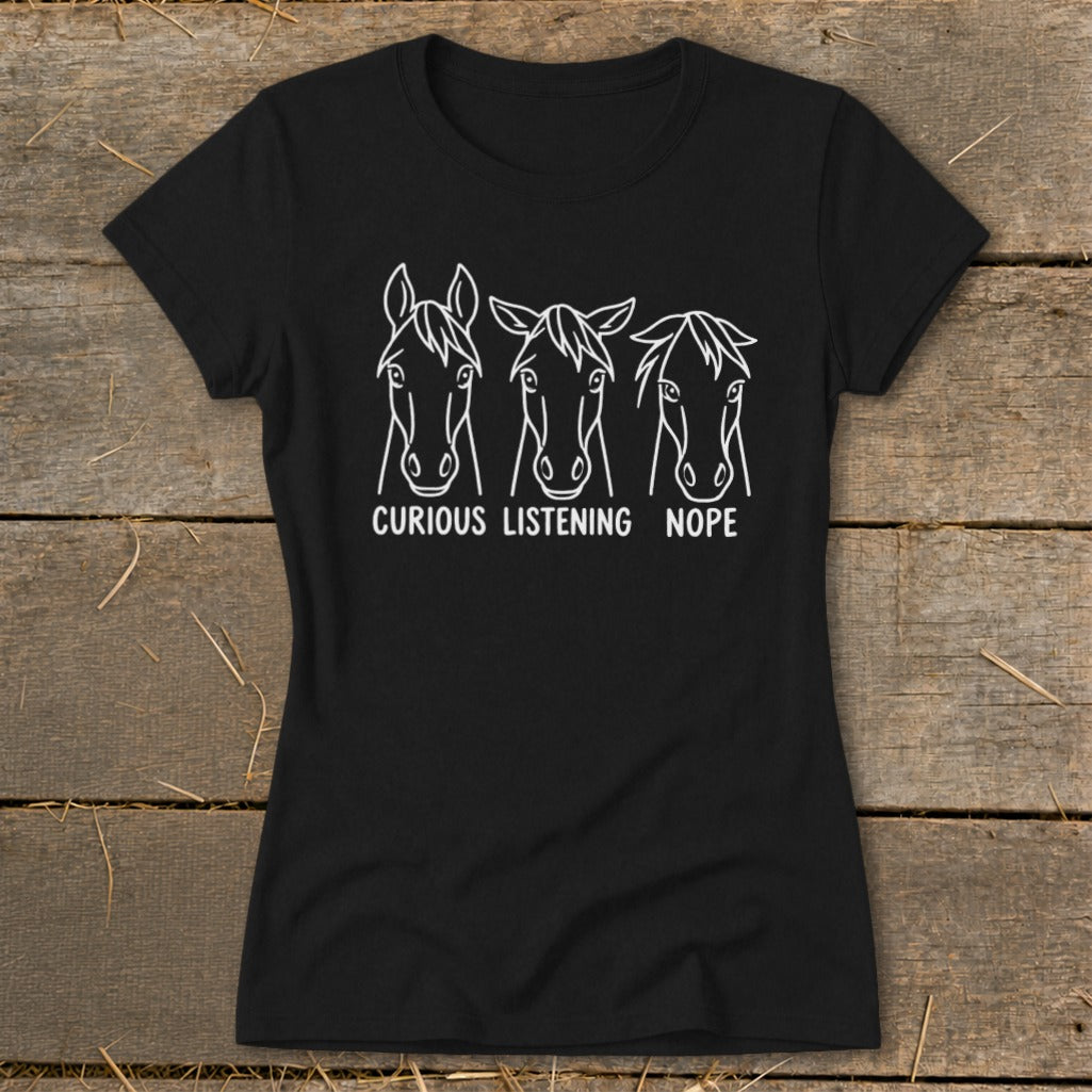 A black short-sleeved t-shirt featuring three horse head illustrations with the captions Curious, Listening, and Nope.