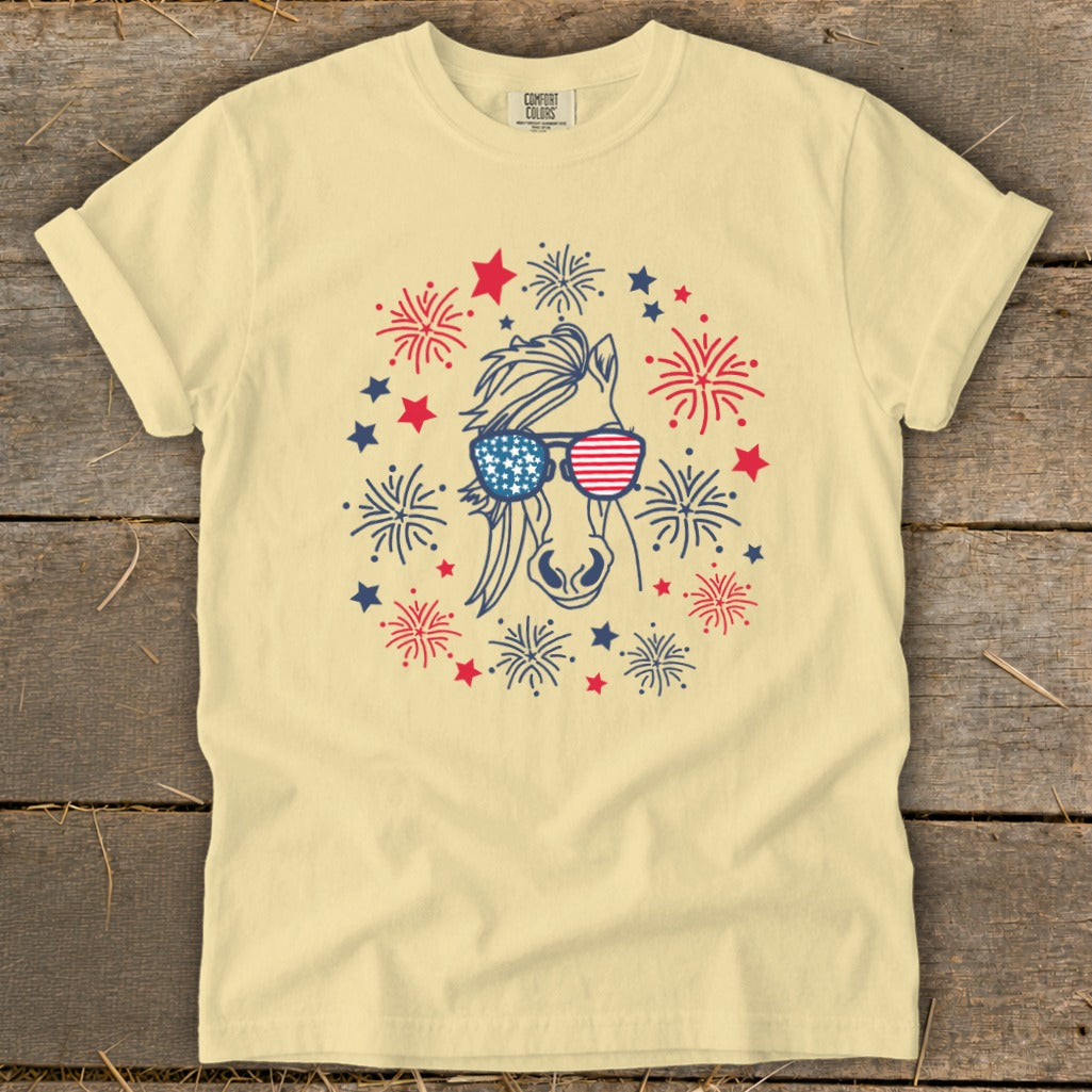 Yellow t-shirt with a horse wearing American flag sunglasses surrounded by fireworks and stars.