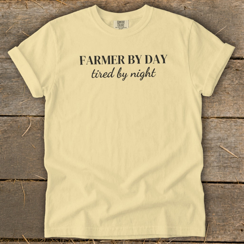 Light yellow t-shirt with "Farmer by day, tired by night" printed in black text.
