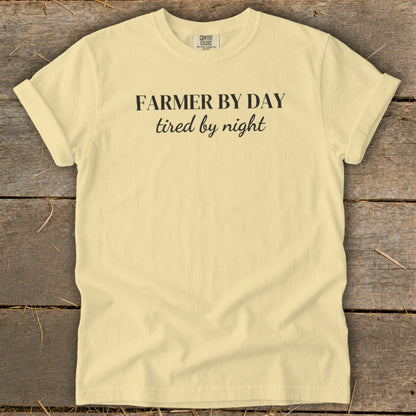 Light yellow t-shirt with "Farmer by day, tired by night" printed in black text.
