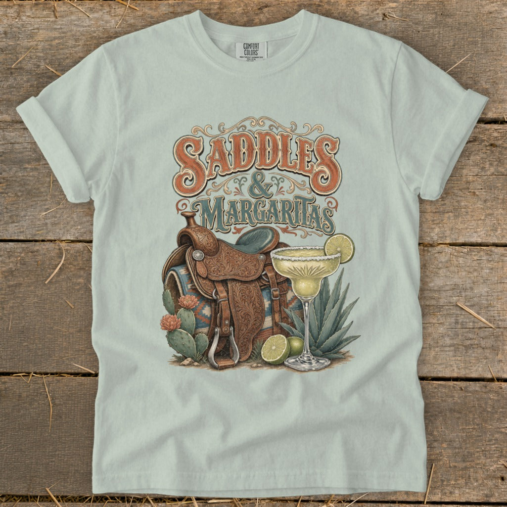 Saddles & Margaritas graphic on light green t-shirt with cowboy saddle and margarita.
