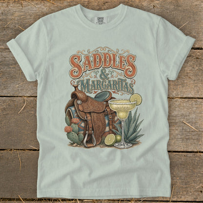 Saddles & Margaritas graphic on light green t-shirt with cowboy saddle and margarita.