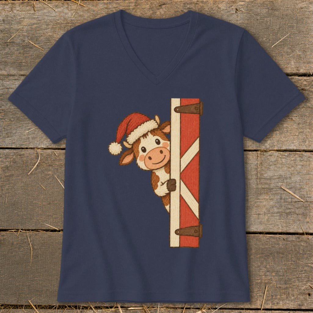 Cartoon cow wearing a Santa hat peeking around a red barn door.