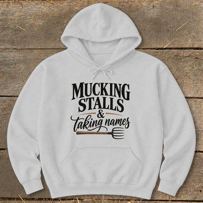 White hoodie with "MUCKING STALLS & taking names" text and a pitchfork graphic.