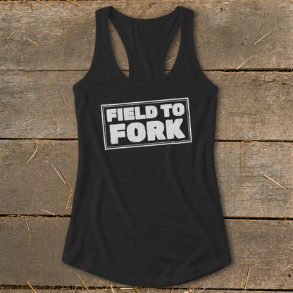 A black racerback tank top featuring the text Field to Fork in white on a rustic wooden background.