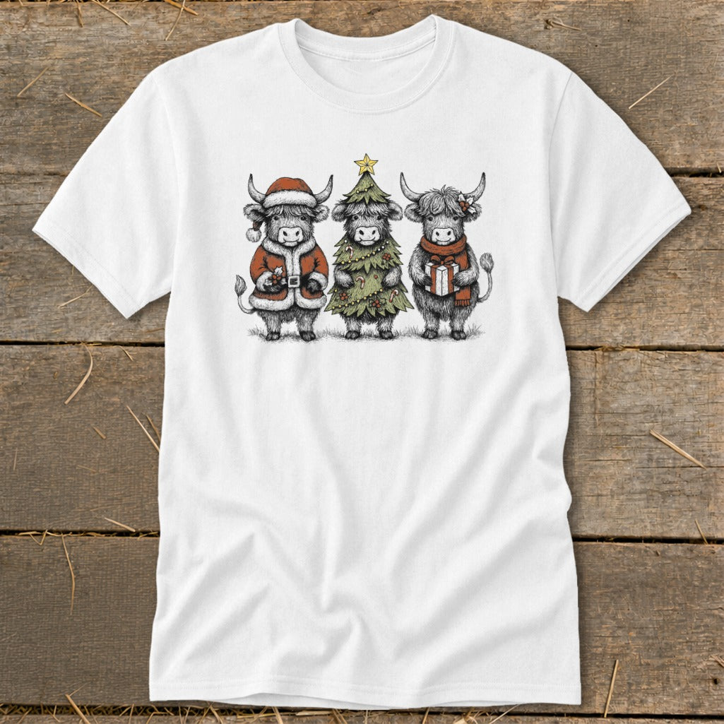 White t-shirt featuring three highland cows in festive Christmas attire.