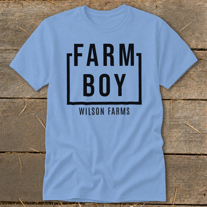 Light blue t-shirt with black text "FARM BOY WILSON FARMS" inside a black square.