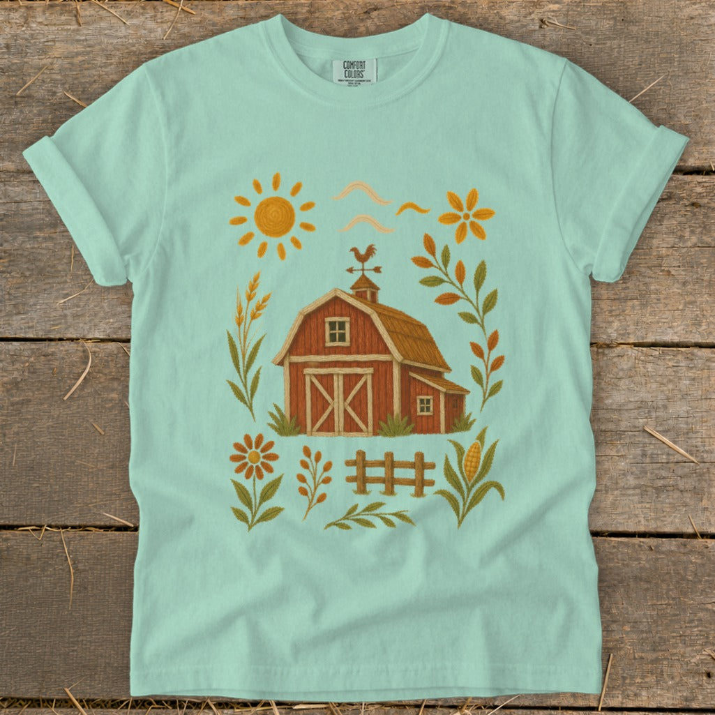 Mint t-shirt with a red barn, sun, flowers, wheat, and corn illustration.