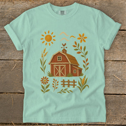 Mint t-shirt with a red barn, sun, flowers, wheat, and corn illustration.