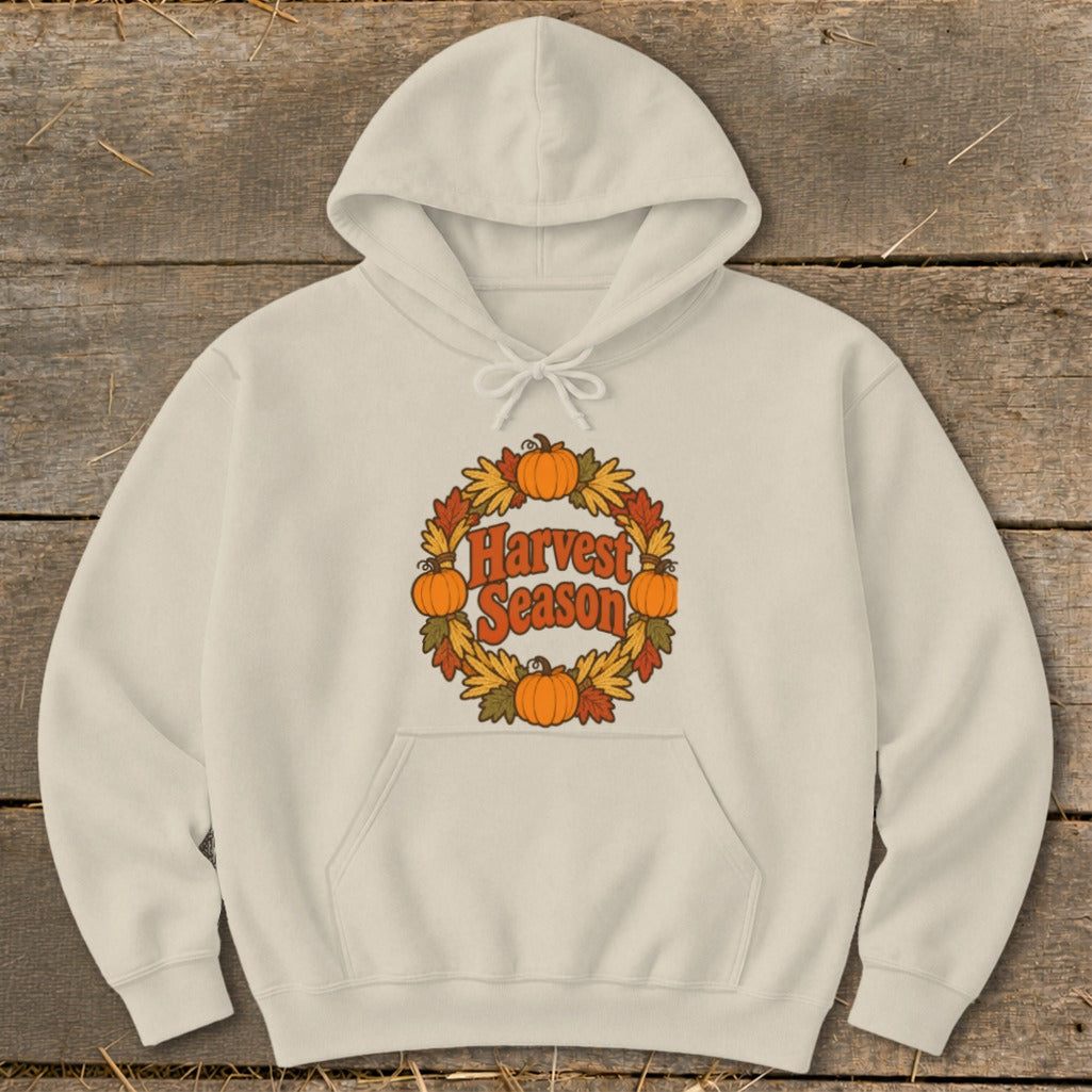 Cream hoodie with "Harvest Season" text surrounded by a wreath of pumpkins and autumn leaves.