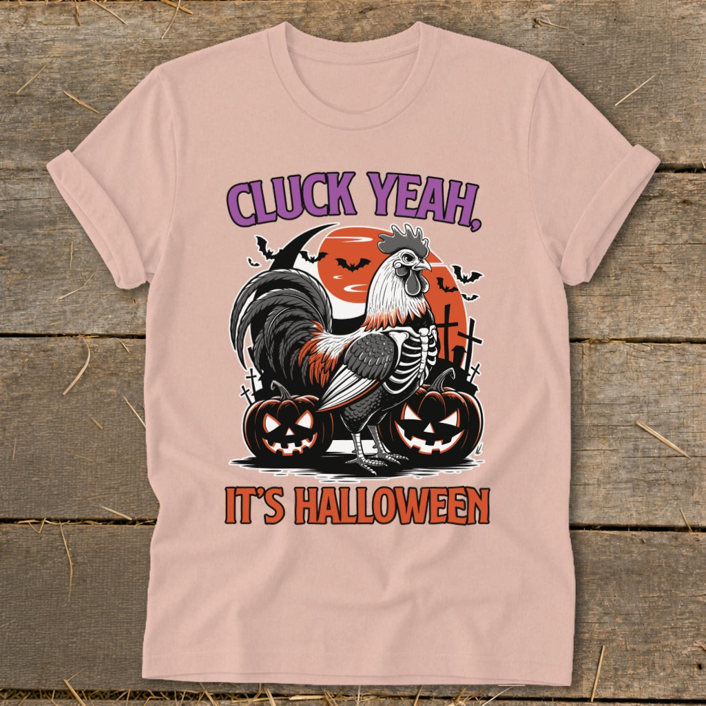 Skeleton rooster with pumpkins and bats on a pink t-shirt, text says "Cluck Yeah, It's Halloween".