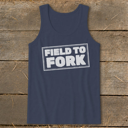 Dark blue tank top featuring the white text FIELD TO FORK inside a distressed rectangular box, laid flat on a rustic wooden background.