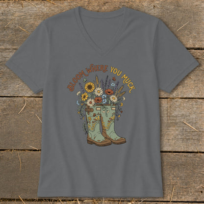 Gray v-neck shirt with "Bloom Where You Muck" text over cowboy boots and flowers.