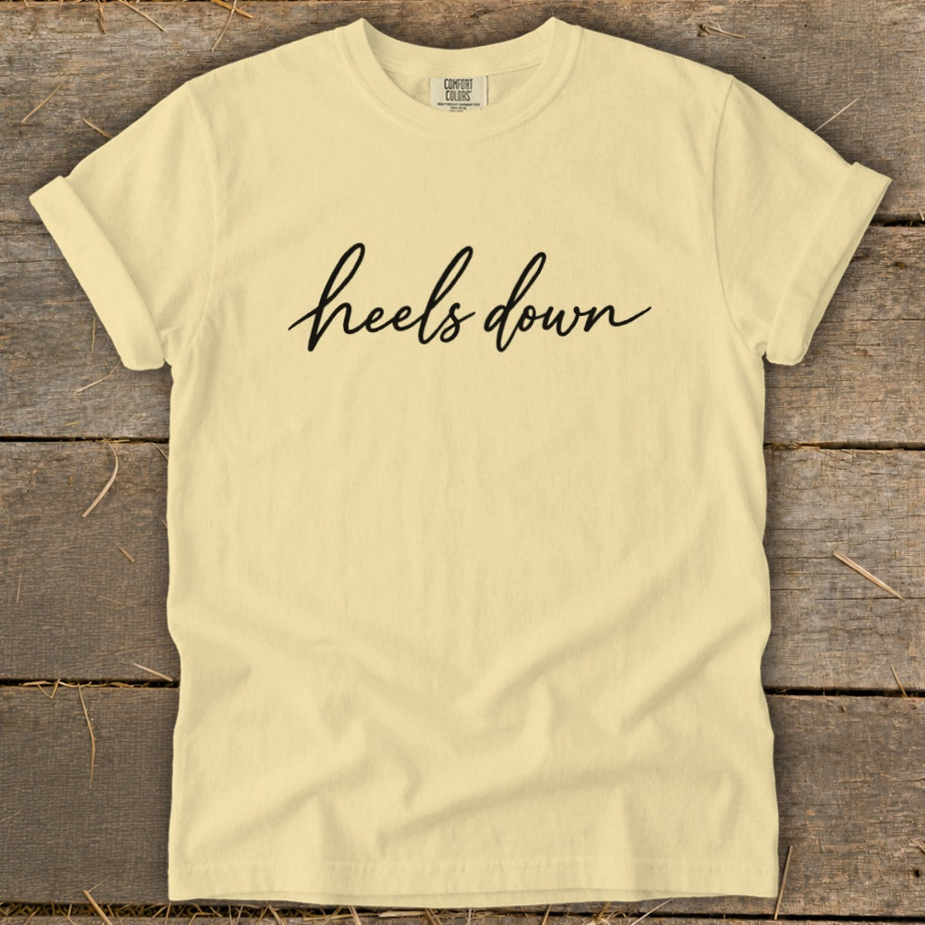 Light yellow t-shirt with "heels down" text in black script.