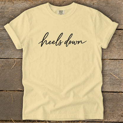 Light yellow t-shirt with "heels down" text in black script.