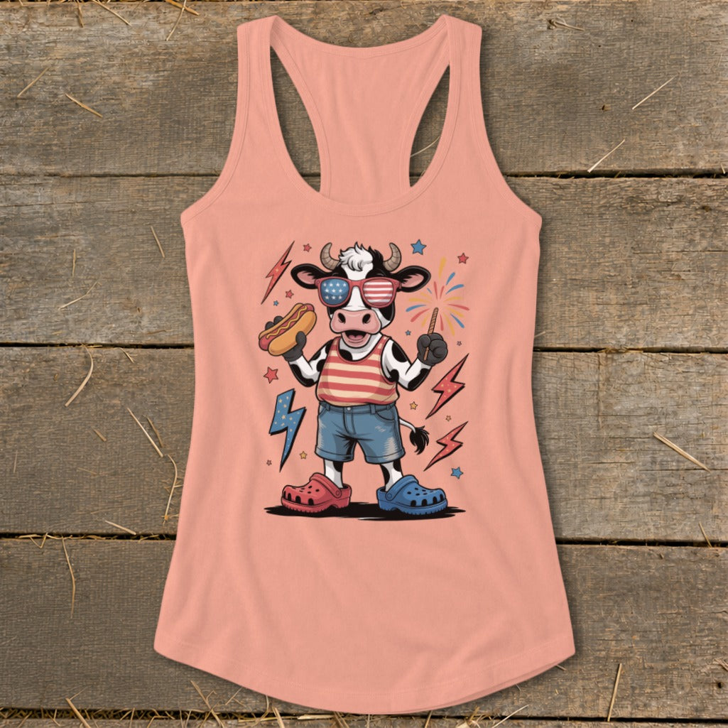Cartoon cow in American flag sunglasses holds hot dog and sparkler with fireworks.