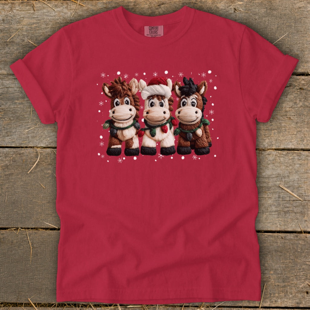 Three cartoon horses with Christmas lights and Santa hat on red t-shirt.