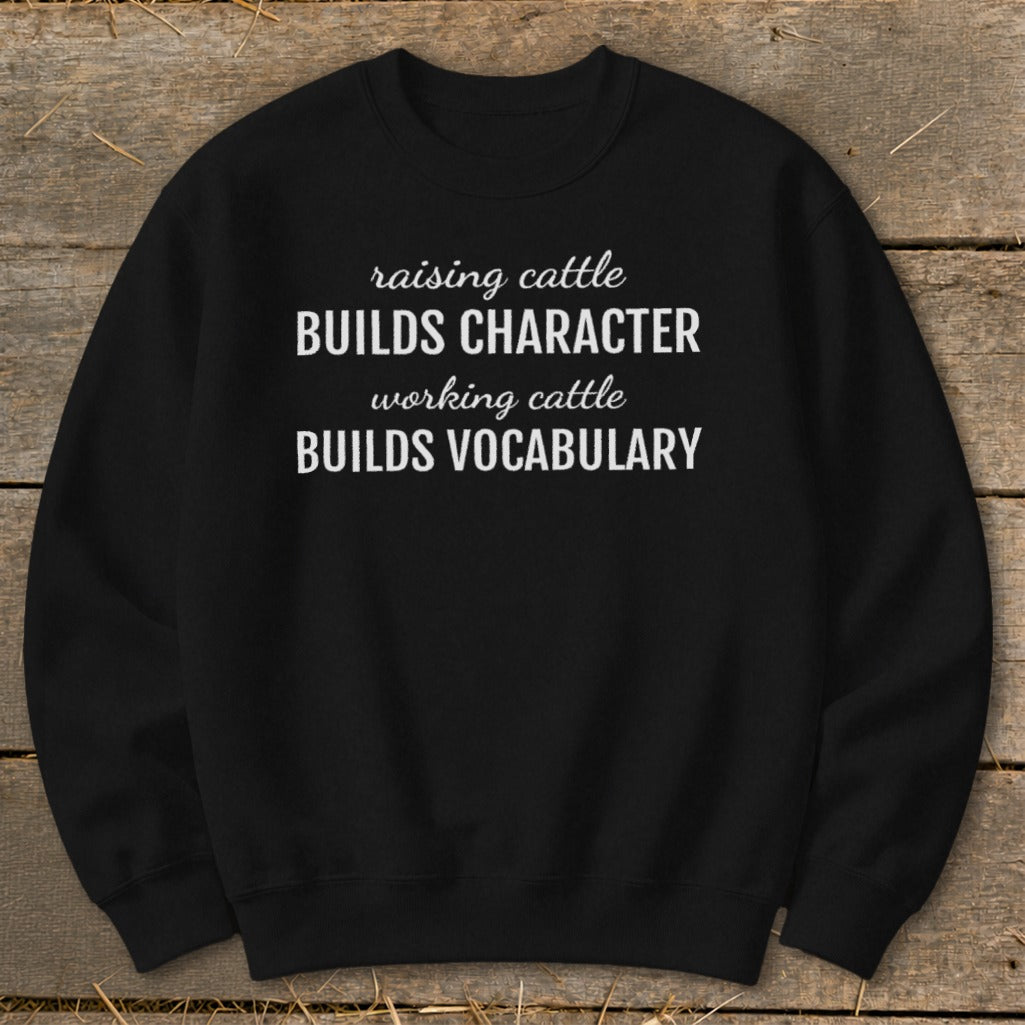 Black sweatshirt with white text: "raising cattle BUILDS CHARACTER working cattle BUILDS VOCABULARY".