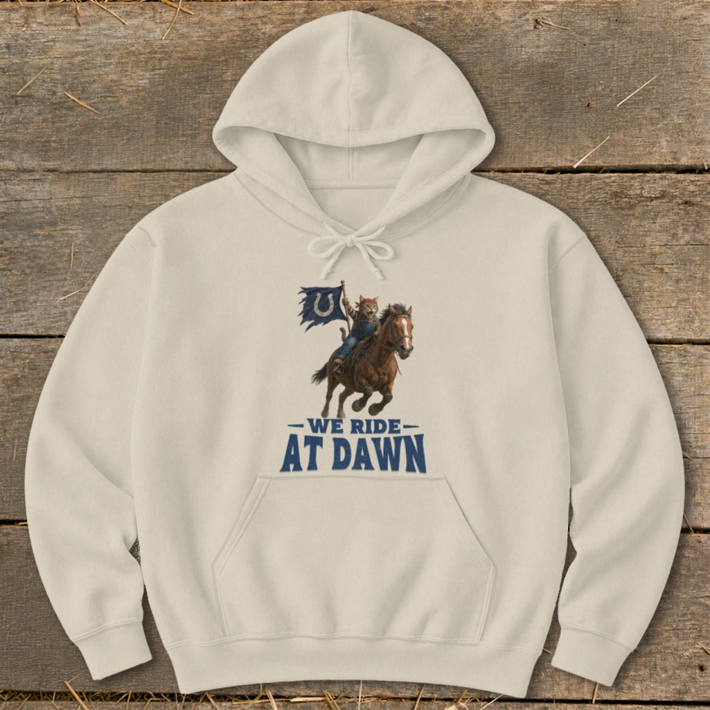 Cream hoodie with a graphic of a cat riding a horse and flag, reading "We Ride At Dawn".