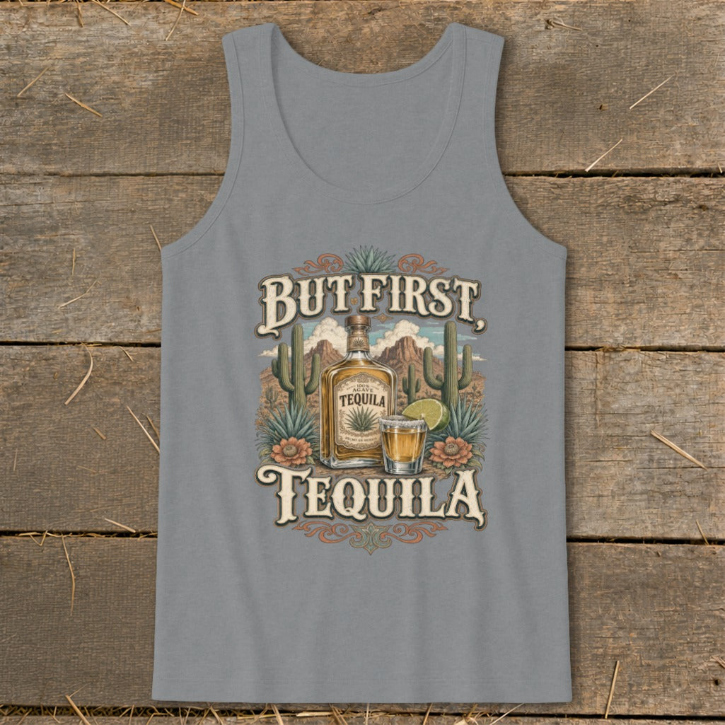A grey tank top featuring a graphic of a tequila bottle, shot glass, cacti, and text that reads But First, Tequila.