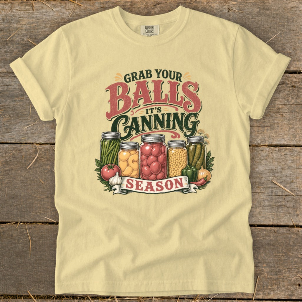 Pale yellow t-shirt with "Grab Your Balls It's Canning Season" graphic and mason jars of vegetables.