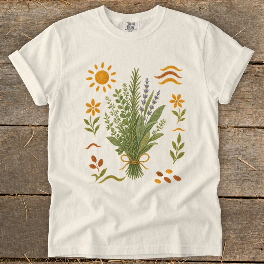 White t-shirt with embroidered bouquet of herbs and flowers, sun, and waves.