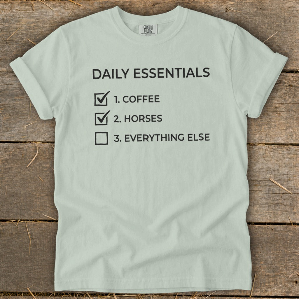 Light blue t-shirt with "Daily Essentials" and a checklist for coffee, horses, and everything else.