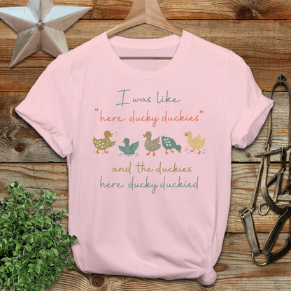Light pink t-shirt with colorful ducks and text: "I was like 'here ducky duckies' and the duckies here ducky duckied."