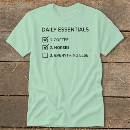 Light green t-shirt with black text listing "Daily Essentials: 1. Coffee, 2. Horses, 3. Everything Else".