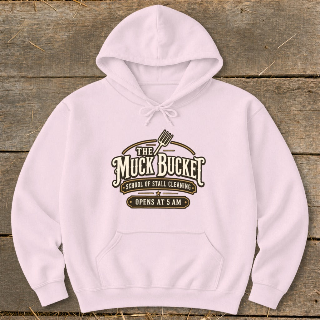 Pink hoodie with "The Muck Bucket School of Stall Cleaning Opens at 5 AM" logo.