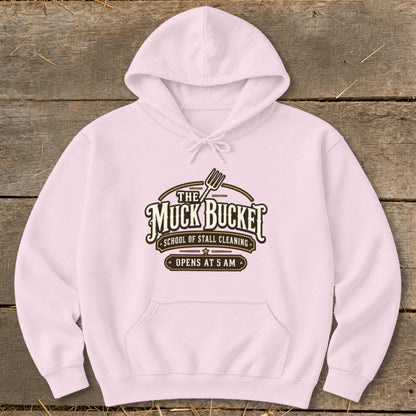 Pink hoodie with "The Muck Bucket School of Stall Cleaning Opens at 5 AM" logo.