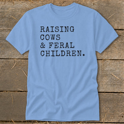 Light blue t-shirt with black text that reads "RAISING COWS & FERAL CHILDREN."