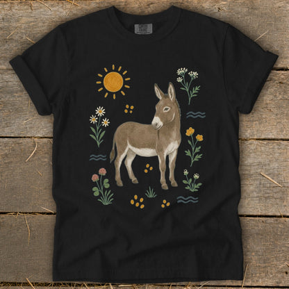 Black t-shirt with a watercolor illustration of a donkey surrounded by flowers and sun.