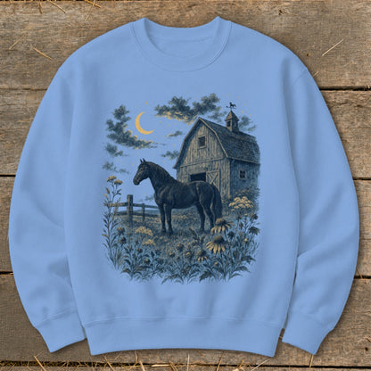 Black horse in field with barn, moon, and stars graphic on light blue sweatshirt.