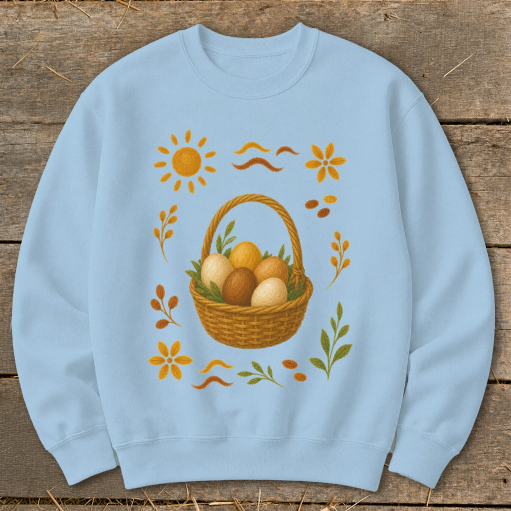 Light blue sweatshirt with a woven basket of Easter eggs and surrounding floral and sun graphics.