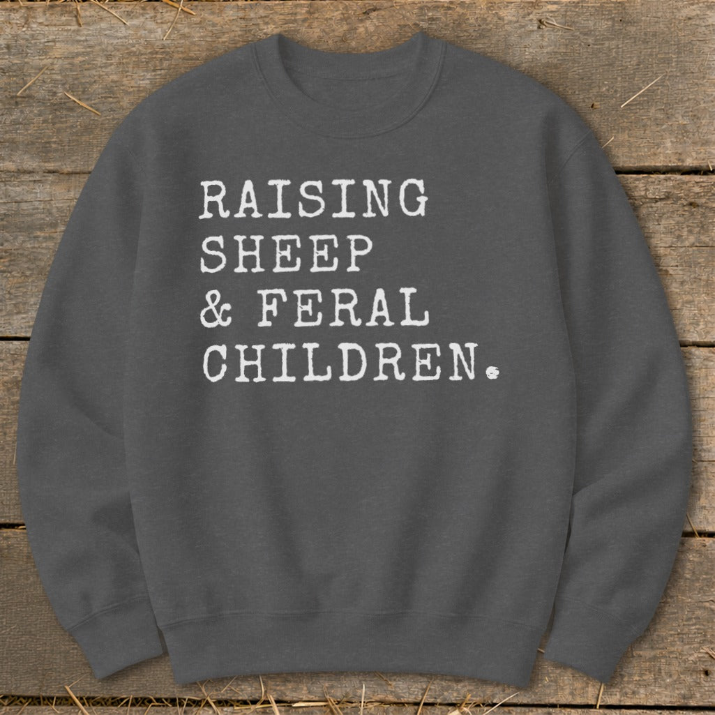 Grey sweatshirt with white text: "RAISING SHEEP & FERAL CHILDREN."