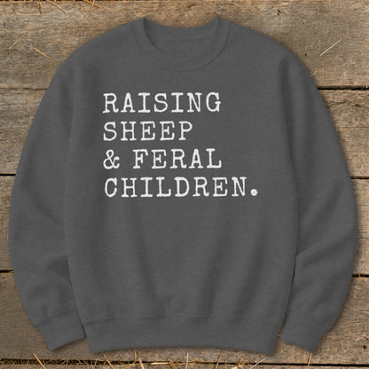 Grey sweatshirt with white text: "RAISING SHEEP & FERAL CHILDREN."