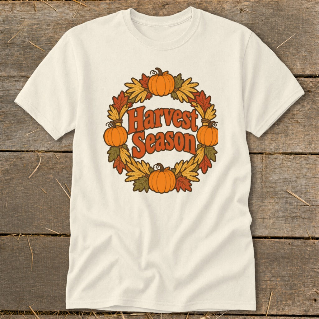 Cream t-shirt with "Harvest Season" text inside a circular wreath of pumpkins and autumn leaves.