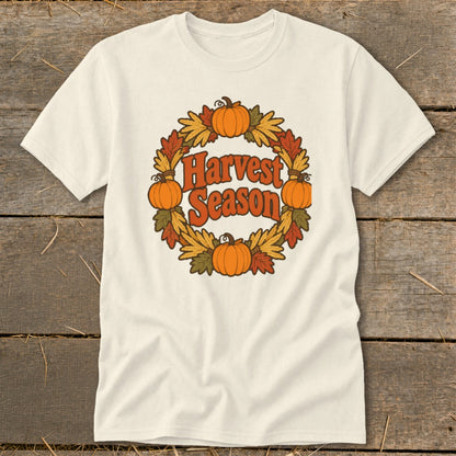 Cream t-shirt with "Harvest Season" text inside a circular wreath of pumpkins and autumn leaves.