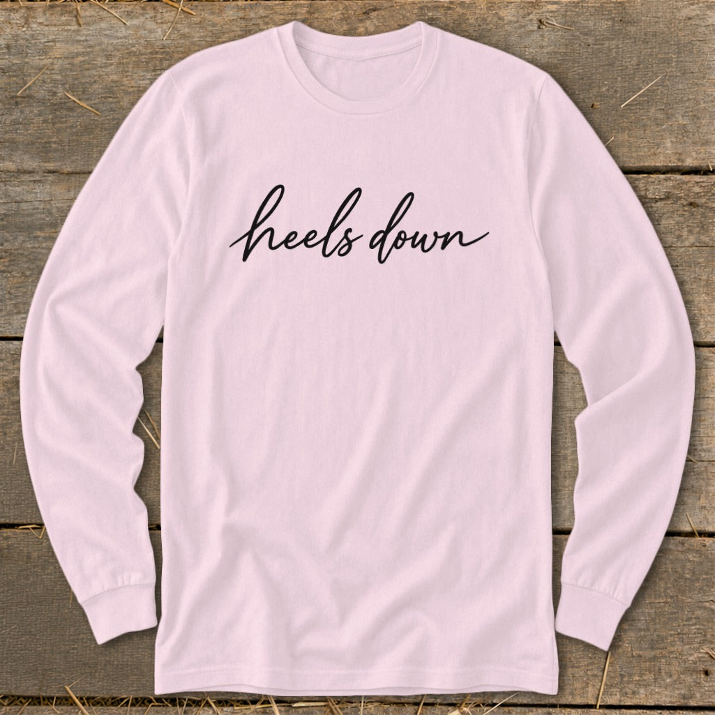 Pink long-sleeve shirt with "heels down" text in black script.