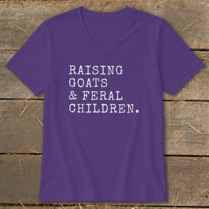 Purple v-neck t-shirt with white text: Raising Goats & Feral Children.