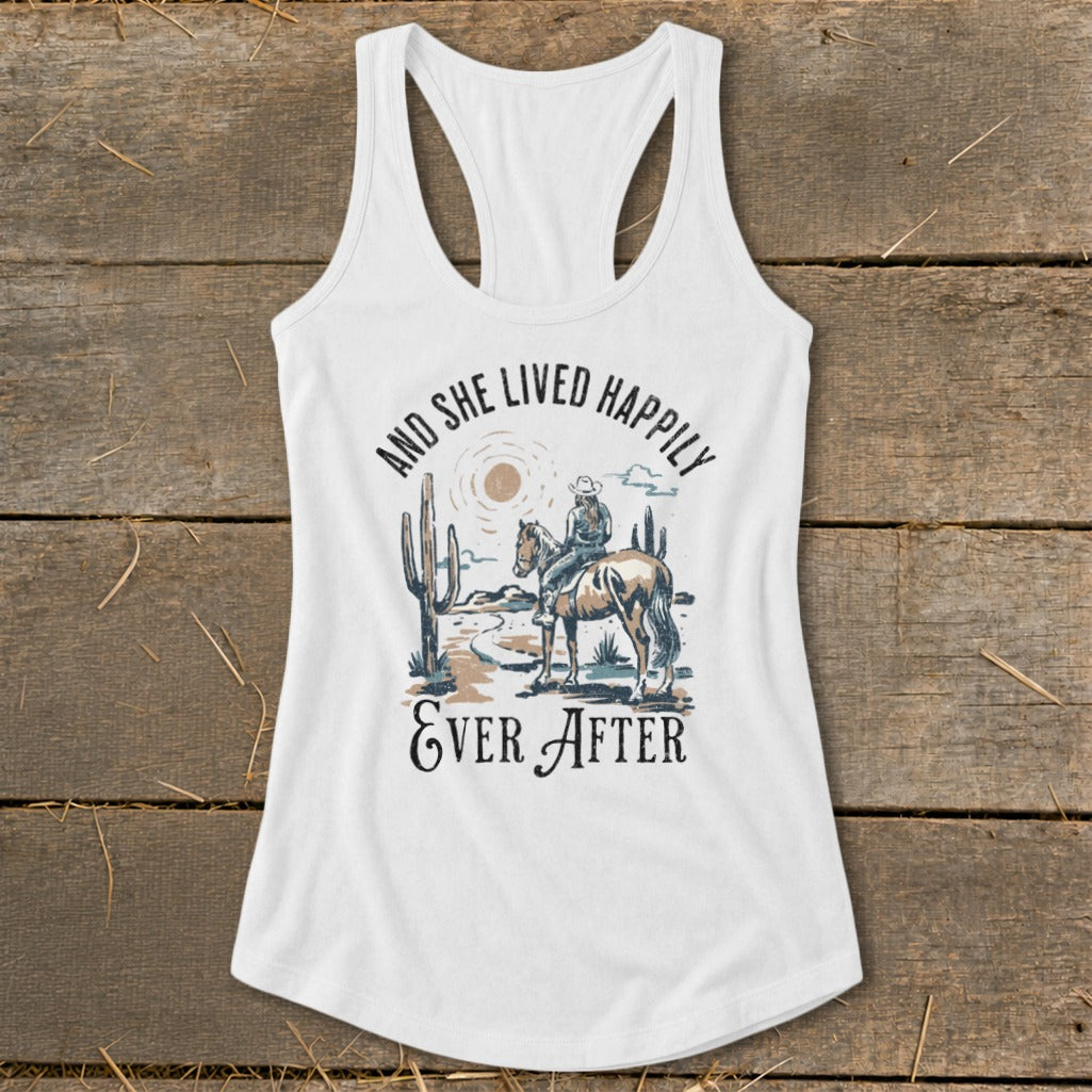 White tank top with graphic of a cowgirl on a horse and text "And She Lived Happily Ever After".