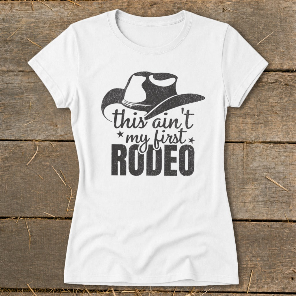 White t-shirt with a cowboy hat graphic and text "this ain't my first RODEO".